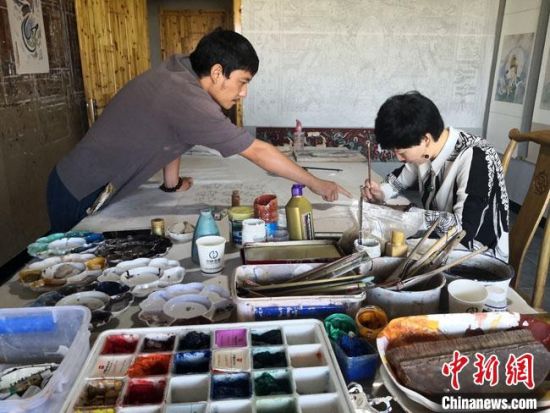 圖為2020年8月下旬，敦煌“80后”畫家張杰龍(左)在為云南麗江“學生”莫北講解敦煌壁畫的繪畫技巧。　馮志軍 攝