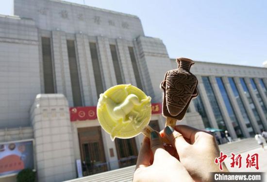 2021年7月30日，游客手拿“銅奔馬”“彩陶瓶”造型的雪糕，在甘肅省博物館前拍照打卡?！「哒?攝