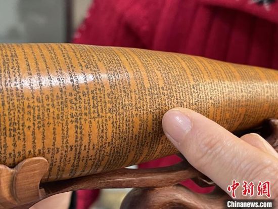圖為長約二十公分的長條葫蘆雕刻佛教經文作品。　張婧 攝