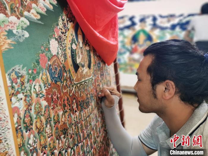 圖為更登才讓的徒弟繪畫唐卡?！?zhí)砀?攝