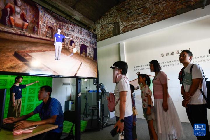 7月22日，游客體驗“尋境敦煌——數(shù)字敦煌沉浸展”后，在虛擬演播廳拍攝一段真人與洞窟虛擬場景交互的視頻。新華社記者 郎兵兵 攝</p>
<p>