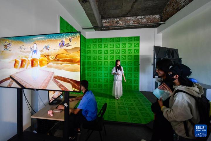 7月22日，游客體驗“尋境敦煌——數(shù)字敦煌沉浸展”后，在虛擬演播廳拍攝一段真人與洞窟虛擬場景交互的視頻。新華社記者 郎兵兵 攝</p>
<p>